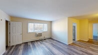 Located at 12 Zachary Ln in Trenton, NJ, this single-floor unit has been thoughtfully updated throughout, offering a clean and functional living environment. The flooring is a consistent, durable wood-look laminate in a cool grey-brown tone that runs throughout the living spaces and bedrooms, lending a cohesive and modern aesthetic to the interior.

The main living area is generously sized, featuring a large window that brings in natural light and offers views of the surrounding greenery. A wall-mounted air conditioning unit and a baseboard heating system provide year-round climate control. An adjacent kitchen is visible through an open passageway and includes stainless steel appliances.

The bedrooms are well-proportioned, with neutral beige walls and windows that allow natural light to filter in. One bedroom features two side-by-side closets with rod storage, while another includes a single closet, offering practical storage solutions throughout.

The bathroom stands out with its elegant marble-style tile work covering the walls of the tub-shower surround, complemented by a white soaking tub, a single vanity, and a window fitted with blinds for privacy and light control. The kitchen area also benefits from a window overlooking the outdoors, with marble-look countertops adding a refined touch.