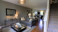 Located at 4115 Britton Parkway in Hilliard, Ohio, this well-appointed three-story home offers a thoughtfully designed layout with refined finishes throughout. The main living area showcases an open-concept floor plan where the living room, dining area, and kitchen flow seamlessly together, creating an inviting and functional space ideal for both everyday living and entertaining. Rich hardwood flooring runs throughout the main level, complementing the warm, neutral color palette anchored by sophisticated gray tones on the walls. The living room is highlighted by a stylish geometric pendant light fixture that adds a contemporary focal point overhead, while large windows invite natural light into the space. The kitchen features dark cabinetry paired with modern appliances and a raised bar counter, providing additional seating and workspace. A dedicated dining area sits between the living room and kitchen, making the entire main level feel cohesive and well-connected. The home extends across three floors, offering ample room for a variety of living arrangements. Throughout the space, the combination of modern lighting, warm wood tones, and carefully chosen finishes creates an ambiance that is both elegant and comfortable — a welcoming residence in the heart of Hilliard, Ohio.