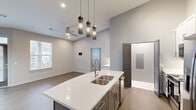 Located at 3040 N Hills Blvd in North Little Rock, Arkansas, this well-appointed two-bedroom, one-bathroom residence delivers a modern aesthetic across a single thoughtfully designed floor. The open-concept living and dining area greets you with warm wood-look flooring, a stylish ceiling fan, and a contemporary chandelier, with natural light streaming in through large windows framed by clean white blinds. The kitchen serves as the centerpiece of the home, showcasing dramatically soaring ceilings, a spacious quartz-topped island with a double stainless steel sink and sleek pendant lighting overhead. White shaker cabinetry, a subway tile backsplash, and a full suite of stainless steel appliances — including a French door refrigerator, electric range, and built-in microwave — complete this highly functional and visually striking space. Both bedrooms offer plush carpeting, ceiling fans, and windows that bring in ample natural light. The primary bedroom provides a comfortable and generously sized retreat. The bathroom is a standout feature, finished with marble-look tile floors and walls, a frameless glass walk-in shower with a rainfall showerhead, and a clean white vanity. A dedicated laundry area and closet add everyday convenience to this polished, move-in ready home.