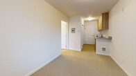 Located in Seattle's University District at 1100 NE 47th St, this efficiently designed one-bedroom, one-bathroom unit offers a thoughtful layout that maximizes every square foot. The open-concept living and kitchen area features light wood cabinetry with sleek bar pulls, a neutral quartz-style countertop, and under-cabinet appliances — all set against crisp white walls that keep the space feeling bright and clean. Soft carpet flooring extends throughout the main living area and into the bedroom, adding warmth underfoot.

The bedroom is a comfortable, well-proportioned space bathed in natural light through a large window fitted with horizontal blinds. Clean white walls and neutral carpet create a calm, versatile environment. A dedicated closet provides practical storage.

The bathroom is neatly appointed with a wood-toned vanity, an undermount sink with contemporary fixtures, a lighted mirror, and a full soaking tub with shower combination — all finished in a clean white palette. A hallway entry connects each area of the unit efficiently, with a utility panel conveniently accessible near the front door. This unit's streamlined design and modern finishes make it a practical and comfortable space in a prime Seattle neighborhood.