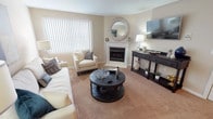 This single-floor residence offers a thoughtfully designed layout with a warm, neutral color palette throughout. The inviting living room serves as the heart of the home, centered around a classic white-mantled fireplace with a decorative round mirror above it. Plush carpeting, vertical blinds allowing natural light, and ample space for seating create a comfortable and welcoming atmosphere.

The kitchen is functionally designed with an abundance of white cabinetry, dark granite-style countertops, hardwood-style flooring, and a full suite of black appliances including a gas range, microwave, refrigerator, and dishwasher. A stainless steel sink and generous counter space make this kitchen well-suited for everyday cooking.

The primary bedroom is a serene retreat featuring soft carpeting and a ceiling fan, with access to a spacious walk-in closet outfitted with wire shelving on multiple walls for organized storage. A second bedroom offers a similarly calm aesthetic with mirrored closet doors. The full bathroom is clean and efficient, featuring tile flooring, a wood-toned vanity, and a shower-tub combination. A dedicated laundry area with a full-size washer and dryer adds everyday convenience to this comfortable home.