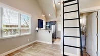 Located at 2027 W Powell Blvd in Gresham, Oregon, this efficiently designed two-bedroom, one-bathroom unit makes smart use of its single-floor layout. Light wood-style flooring runs throughout, providing a clean, cohesive look that ties each room together.

The kitchen is a standout feature, boasting vaulted ceilings that lend an open, airy feel despite the compact footprint. Dark navy cabinetry is paired with bright white quartz countertops, a stainless steel sink, and stainless steel appliances. A peninsula with corbel-supported counter seating connects the kitchen to the living area, offering a casual dining option. Multiple windows flood the space with natural light.

The primary bedroom features a sliding barn-style closet door and direct access to a private balcony through glass French doors, inviting natural light and outdoor views. The second bedroom is a bright, versatile space with a window fitted with wood blinds and light wood-style flooring.

A shared full bathroom includes a walk-in shower with floor-to-ceiling tile surround, a white vanity with sink, and a mirror. Clean, neutral tones throughout create a calm and welcoming ambiance.

Arched interior doors and crisp white trim provide classic finishing touches, completing this thoughtfully updated unit in Gresham.