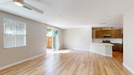 This two-story home is designed with a clean, contemporary aesthetic throughout. The main level centers on an open-concept living area finished with light hardwood-style flooring that extends seamlessly from the living space toward the kitchen. A sliding glass door fills the room with natural light and provides direct access to a fenced outdoor area, while a ceiling fan overhead adds functional comfort. The kitchen is thoughtfully appointed with taupe shaker-style cabinetry, white quartz countertops, a classic subway tile backsplash, and stainless steel appliances including a gas range, built-in microwave, and dishwasher.

Upstairs, the home continues with carpeted bedrooms, each offering a calm, neutral palette. One room connects to a walk-in closet with wire shelving on both sides, which in turn leads to a bathroom fitted with tile flooring, a vanity with white countertop, and clean finishes throughout. A bright upper landing area features a skylight and ceiling fan, adding an airy, open quality to the second floor.

The attached garage is spacious, drywalled, and equipped with an automatic opener, offering ample room for vehicles or storage, with a side door providing convenient exterior access.