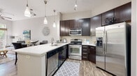 Located at 730 Hawthorne Lane in Charlotte's vibrant 28204 zip code, this single-floor residence offers a thoughtfully designed open-concept layout with modern finishes throughout. The kitchen serves as a central highlight, featuring rich dark-espresso cabinetry extending to the ceiling, a classic white subway tile backsplash, gleaming quartz countertops, a peninsula with an undermount sink, and a full suite of stainless steel appliances including a side-by-side refrigerator with ice maker, electric range, built-in microwave, and dishwasher. Stylish pendant lighting and a track rail system illuminate the space effectively. Wood-style plank flooring flows seamlessly through the kitchen, dining, and living areas, lending warmth and continuity. The dining area sits adjacent to the kitchen, while the living room opens to a private balcony through a large sliding glass door, filling the room with natural light and offering leafy outdoor views. The bedroom is generously proportioned with wood-style flooring, a walk-in closet, and a large window overlooking greenery. The bathroom is finished with large-format tile flooring, a dark-wood vanity with a white countertop, and a tub-shower combination. Neutral tones throughout create a clean, contemporary ambiance.