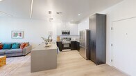 This thoughtfully designed one-bedroom, one-bathroom residence in Phoenix, AZ offers a modern aesthetic with clean lines and a bright, open feel throughout. Light wood flooring flows seamlessly across the living areas, complementing the crisp white walls and contemporary finishes.

The kitchen is a standout feature, showcasing two-tone cabinetry with sleek white upper cabinets and dark lower cabinets, stainless steel appliances including a range, microwave, and full-size refrigerator, and a generous peninsula with a quartz-style countertop and an integrated sink. An artistic sculptural pendant light anchors the space above, adding a modern design touch alongside recessed lighting.

The living area connects openly to the kitchen, creating an efficient and functional layout ideal for everyday living. The bedroom offers a comfortable, well-proportioned space with a sliding door closet, light wood floors, a ceiling fan, and a large window that frames outdoor views of the surrounding Phoenix landscape, filling the room with natural light.

The bathroom features a walk-in shower with white subway tile, matte black fixtures, and wood-look flooring, delivering a clean and contemporary finish. A hallway connects the main living spaces, contributing to a logical and easy-to-navigate floor plan. Overall, the space combines modern design with practical functionality in a well-appointed Phoenix location.