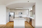 Located at 99 Gorge Rd in Edgewater, NJ, this well-appointed 2-bedroom, 2-bathroom residence offers a bright and modern living experience with impressive views of the Hudson River and the New York City skyline. Light hardwood flooring flows throughout the entire unit, creating a warm, cohesive aesthetic against the clean white walls and trim.

The open-concept kitchen is a standout feature, equipped with stainless steel appliances including a refrigerator, range, microwave, and dishwasher. Soft gray shaker-style cabinetry pairs with white quartz countertops and a subway tile backsplash, while a central island provides additional prep and seating space. The adjacent living room is generously sized with large windows that invite abundant natural light.

The primary bedroom is spacious and includes floor-to-ceiling sliding glass doors opening to a private balcony with sweeping river and city views. The second bedroom also benefits from large windows framing scenic outdoor vistas. Both bedrooms feature the same light hardwood flooring found throughout the residence.

The two bathrooms are finished with warm stone-toned tiles. The primary bath includes both a soaking tub and a separate glass-enclosed shower, while the second bath features a glass sliding door shower enclosure. Multiple hallways and a closet provide practical storage and circulation throughout the home.