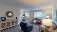 This single-story residence offers a well-organized layout connecting the main living areas in a cohesive, open flow. The living room is generously proportioned, featuring plush carpeting, neutral walls, and ample space for multiple seating arrangements. Ceiling fans are present throughout, providing both function and a casual aesthetic. The living area transitions naturally into a dedicated dining space, which is finished with light hardwood-style flooring, a ceiling fan with light fixture, and a large window that allows natural light and views of surrounding greenery.

The kitchen is equipped with stainless steel appliances, including a gas range and over-the-range microwave, complemented by a classic white subway tile backsplash, light wood cabinetry, and granite-style countertops. Light-toned flooring continues the cohesive design throughout this area.

The residence includes two bedrooms, each with carpeted floors, ceiling fans, and windows providing natural light. One bedroom features a sliding-door closet with built-in shelving, while the other offers comfortable proportions with space for bedside furnishings. The bathroom includes a full tub-and-shower combination with clean white tile surround and chrome fixtures, maintaining a simple, functional design throughout.