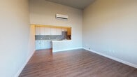 Located at 400 Fourth Ave W in Olympia, Washington, Unit 405 is a single-floor space featuring a contemporary design with notable architectural details, including soaring ceilings that lend an open, airy feel throughout. The main living area is finished with warm wood-look flooring and neutral-toned walls, creating a clean and versatile environment. A wall-mounted mini-split system provides efficient climate control directly in the living space.

The kitchen is a standout feature, designed as a pass-through with a peninsula counter that opens to the main living area. It is outfitted with full-height cabinetry in a modern gray finish, a textured penny-tile backsplash, light countertops, and a complete suite of stainless steel appliances including a range, microwave, and refrigerator. Ample upper and lower cabinet storage maximizes functionality.

A separate entry area features dark hardwood-style flooring, transom windows above a large street-facing window, and a glass-panel door that allows natural light and views of the surrounding streetscape. The bathroom is well-appointed with a gray vanity with drawers, a mirrored cabinet, tile accents, and wood-look flooring consistent with the rest of the unit. The overall ambiance is modern, clean, and move-in ready.
