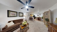 Located at 3250 S Town Center Dr in Las Vegas, NV, this 2-bedroom, 2-bathroom residence offers a well-designed single-level layout that maximizes functionality. The open-concept main area seamlessly connects the living room, dining room, and kitchen, creating a cohesive and social atmosphere. The living room features plush carpeting and a ceiling fan, with a front entry that allows natural light to filter through window treatments. The kitchen is equipped with warm honey-toned cabinetry, light stone countertops, wood-style flooring, and black appliances including a range, microwave, and refrigerator. The adjacent dining area, also with wood-style flooring, offers a comfortable space for everyday meals. Both bedrooms are carpeted and feature ceiling fans, with the generously sized primary bedroom providing a comfortable retreat. The two bathrooms are functional and well-appointed, with one featuring a walk-in tiled shower with black hardware and wood-style flooring. Additional highlights include two closets, a dedicated laundry area, and a connecting hallway that provides a logical flow between spaces. The overall ambiance is warm and inviting throughout.
