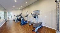 This compact yet comprehensive fitness center occupies a single-story, 340-square-foot space at 300 Peppertree Way, Pittsburg, CA. The facility boasts a thoughtful layout that maximizes functionality within its limited footprint. The room features warm wood flooring that contrasts nicely with the neutral-toned walls, creating an inviting atmosphere for exercise.

Recessed lighting fixtures are strategically placed throughout the ceiling, ensuring even illumination across the entire space. Large mirrors line one wall, visually expanding the room and allowing users to monitor their form during workouts. The center is well-equipped with a variety of modern fitness machines, including multiple cardio options such as treadmills, ellipticals, and stationary bikes. A multi-functional weight training station is also present, catering to strength training enthusiasts.

The layout is designed for easy navigation, with clear pathways between equipment. Windows provide natural light and views to the outside, contributing to a pleasant workout environment. Attention to detail is evident in the inclusion of amenities like wall-mounted televisions, sanitization stations, and posted safety guidelines, ensuring a comfortable and hygienic exercise experience for all users.