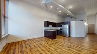 Located at 620 Frankfort Ave in Cleveland's vibrant Tremont neighborhood, this single-floor unit showcases an industrial-loft aesthetic that blends raw architectural character with modern finishes. The open living area immediately impresses with its soaring ceilings, exposed ductwork, and a slatted ceiling detail that adds warmth and texture overhead. A large ceiling fan enhances the airy, expansive feel of the main living space, which is bathed in recessed lighting throughout.

Rich, warm-toned hardwood flooring extends continuously across the entire unit, grounding the space and complementing the industrial design elements. The kitchen is a standout feature, outfitted with dark espresso cabinetry, granite countertops, and a full suite of stainless steel appliances including a refrigerator, range, microwave, and dishwasher. A central island provides additional prep space and visual separation between the kitchen and living area.

A separate room with whitewashed exposed brick walls and a tall arched window brings in natural light while reinforcing the building's historic character. The combination of original brick, modern fixtures, and open layout creates a cohesive, urban atmosphere well-suited to city living in one of Cleveland's most walkable and culturally rich neighborhoods.