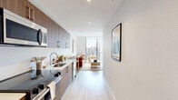 Located in Miami, FL, this thoughtfully designed one-bedroom, one-bathroom residence offers a compact yet efficient single-floor layout with modern finishes throughout. The galley-style kitchen is outfitted with rich wood cabinetry, white quartz countertops, and stainless steel appliances, including a built-in microwave and dishwasher, flowing seamlessly toward the living area. Light wood-tone flooring runs throughout the unit, enhancing the bright, airy atmosphere. The living room is anchored by floor-to-ceiling sliding glass doors that open to a private balcony, offering open views of the Miami skyline and surrounding landscape, and flooding the interior with abundant natural light. The bedroom features a large window, a spacious sliding-door closet, and a clean, minimalist aesthetic with ample room for furnishings. The bathroom is finished with large-format tile, a frameless glass-enclosed walk-in shower, and a modern wall-mounted toilet, creating a spa-like feel. The overall design aesthetic is contemporary and cohesive, with white walls, clean lines, and a neutral palette that maximizes the sense of space throughout this well-appointed Miami residence.
