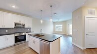 Located at 4434 Cobalt Brook Boulevard in Lutz, Florida, this well-appointed one-bedroom, one-bathroom home offers a thoughtfully designed single-floor layout with modern finishes throughout. The open-concept living area seamlessly connects the kitchen, dining, and living spaces, creating an inviting and functional environment. The kitchen is a standout feature, showcasing crisp white shaker cabinetry reaching to the ceiling, dark granite countertops, a gray subway tile backsplash, and a full suite of stainless steel appliances including a French door refrigerator, range, microwave, and dishwasher. A center island with pendant lighting and an undermount sink adds both style and practicality. The living area is bright and airy, benefiting from natural light through multiple windows and a ceiling fan overhead, with a door providing outdoor access. Wood-look flooring runs consistently throughout the home, lending a warm, cohesive aesthetic. The spacious bedroom includes a ceiling fan, a window with natural light, and access to generous closet storage with built-in wire shelving systems. Three closets in total provide ample storage. The bathroom features a tiled tub-shower combination with marble-style surround. A dedicated laundry area and additional closet spaces round out this efficiently designed home.