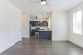 Located at 345 Heatherden Ave in Fayetteville, Georgia, this well-appointed single-floor residence combines modern design with functional living. The open-concept living and kitchen area serves as the heart of the home, anchored by a striking kitchen outfitted with bold navy-blue shaker cabinets, granite-look countertops, a classic white subway tile backsplash, and a full suite of stainless steel appliances including a refrigerator, range, and over-the-range microwave. A peninsula with matching navy cabinetry provides additional workspace and casual seating, while pendant lighting adds a contemporary touch overhead. Rich hardwood-style flooring runs throughout the entire unit, lending warmth and visual continuity across every room. The spacious living area benefits from multiple windows that invite ample natural light, complemented by a ceiling fan for year-round comfort. The bedrooms are generously sized, each featuring large windows with outdoor views and ceiling fans. The bathrooms are finished with the same navy cabinetry and granite countertops seen in the kitchen, paired with tub-shower combinations and wood-look flooring. Barn-style sliding doors add a modern farmhouse accent, visible in the floorplan view. The overall aesthetic is clean, cohesive, and move-in ready.