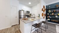 Located at 32000 Gardner Dr in Alpharetta, GA, this thoughtfully designed one-bedroom, one-bathroom residence offers a smart and functional layout across a single floor. The kitchen is a standout feature, showcasing crisp white shaker cabinetry, granite countertops, and a full suite of stainless steel appliances including a refrigerator, microwave, and range. A peninsula with bar seating creates an inviting space for casual dining and entertaining, while light wood-style flooring ties the area together with a clean, contemporary aesthetic. The bedroom is a comfortable retreat, featuring plush carpet, large windows that invite an abundance of natural light and outdoor views of surrounding greenery, and space for a full furniture arrangement. A dedicated closet provides convenient storage. The bathroom is finished with white cabinetry, granite countertops, brushed nickel hardware, and wood-look tile flooring, delivering a polished and cohesive look. Throughout the residence, a neutral white palette creates a bright and airy ambiance, while well-chosen design details lend a modern and welcoming character to every room. This residence offers an efficient yet comfortable living experience in a desirable Alpharetta location.