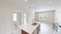 Located at 5045 Burke Road in Pasadena, TX, this single-story, one-bedroom, one-bathroom unit offers a well-designed layout that maximizes functionality and comfort. The entrance leads down a hallway with ample closet storage before opening into the combined kitchen, dining, and living area—the heart of the unit. The kitchen is outfitted with stainless steel appliances, two-tone cabinetry featuring white upper cabinets and warm wood-toned lower cabinets, light quartz countertops, and a central island with a double-basin sink, providing additional prep space and a natural gathering point. Recessed lighting and large windows allow natural light to fill the open-concept living area, which features light wood-tone flooring throughout. A private balcony is accessible directly from the main living space, offering an outdoor retreat. The bedroom is a generously sized, carpeted room with a ceiling fan and its own closet space. The bathroom features a tiled tub-shower combination with marble-style wall tile, a modern vanity with quartz countertops, and wood-look tile flooring. A dedicated laundry area adds everyday convenience to this thoughtfully designed unit.
