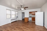 Located at 4200 Grand Ave in Des Moines, Iowa, this efficient single-floor unit offers a well-organized layout that makes the most of its compact footprint. The open living area is bright and welcoming, featuring warm hardwood flooring, white walls, and a ceiling fan with light fixture overhead. Natural light filters in through multiple windows fitted with blinds, while a baseboard radiator and window A/C unit provide year-round climate comfort. The kitchen is thoughtfully arranged with warm oak cabinetry, white tile backsplash, white tile flooring, a gas range, and a full-size refrigerator. A peninsula counter with a white laminate top extends into the living area, creating a natural divide and added prep space. The bathroom retains classic mid-century character, showcasing peach ceramic wall tiles accented by a black tile border, a tiled tub surround, marble-look flooring, a window for natural ventilation, a vanity with sink, and a radiator. A hallway connects the main living spaces to a closet and bathroom, contributing to the unit's organized flow. Overall, the space offers a clean, functional, and straightforward living environment with a warm, timeless aesthetic.