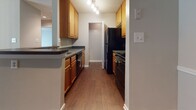 Located at 3231 Coppermill Trace in Henrico, Virginia, this single-floor residence offers a functional and cohesive layout with consistent finishes throughout. The living area serves as the central hub of the home, featuring rich, dark hardwood-style flooring, a ceiling fan with light fixture, and a sliding glass door that fills the space with natural light while providing access to the outdoors. A tile-surround fireplace with a white painted mantel adds a classic focal point to the room.

The kitchen is positioned adjacent to the living area and is accessible via an open pass-through counter. It features warm honey-toned cabinetry, dark countertops, hardwood-style flooring, and a full suite of black appliances including a refrigerator, stove, and dishwasher. A track light fixture illuminates the galley-style layout efficiently.

The bedrooms are carpeted in a neutral tone and offer a calm, comfortable atmosphere. One bedroom includes a sliding glass door with vertical blinds, providing outdoor access and natural light, while another features a window overlooking greenery. Both rooms offer a clean, neutral palette with ample wall space.

The bathrooms are finished with hardwood-style flooring, wood-toned vanity cabinetry, and chrome fixtures. One bathroom includes a full tub-shower combination, while another features a more compact layout. Textured ceilings appear throughout the home, adding subtle character to each room.