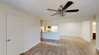 Located at 206 Northlake Dr in Warner Robins, Georgia, this single-floor, 3-bedroom, 2-bathroom home offers a practical and well-organized layout. The combined kitchen and living area serves as the heart of the home, featuring durable hardwood-style flooring, a ceiling fan with light fixture, and a textured ceiling. The kitchen is defined by a pass-through counter with built-in shelving, warm wood cabinetry, and white appliances, creating an open connection to the living space. An entryway area includes dual access doors and additional built-in shelving. The primary bedroom is generously sized, fitted with plush carpet, a ceiling fan, and a sliding glass door that invites natural light and outdoor access. It also includes a walk-in closet with built-in shelving and hanging rods. The two additional bedrooms are carpeted and feature windows with blinds, providing natural light and adequate closet space. Both bathrooms are finished with wood-style tile flooring, vanities with stone-look countertops, dark cabinetry, and a tub/shower combo. One bathroom includes a grab bar for added accessibility. A connecting hallway ties the bedroom wing to the main living areas, completing this efficiently designed single-story home.