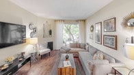 This single-floor residence offers a thoughtfully designed layout with a warm, neutral color palette throughout. The living room serves as the heart of the home, featuring rich hardwood-style flooring, a fireplace, and a large sliding glass door that frames lush outdoor greenery and fills the space with natural light. A comfortable sectional sofa and rustic wood coffee table complete the inviting atmosphere.

The kitchen is efficiently laid out with rich dark wood cabinetry, granite-style countertops, and a full suite of stainless steel appliances including a gas range, over-the-range microwave, and refrigerator. Wood-style flooring continues through this space, adding warmth and cohesion.

The dedicated dining area accommodates a full-sized table with seating for six, accented by a ceiling fan light fixture, framed wall art, and decorative shelving — ideal for both everyday meals and entertaining.

A versatile secondary room features plush carpeting, a window with garden views, and ample space suited for a home office or guest room. The primary bedroom area is carpeted and includes closet storage and stylish accent details.

Two full bathrooms each feature tiled tub-shower combinations with curtain enclosures and clean, bright finishes, providing functional comfort throughout the home.