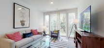 This well-appointed single-floor residence at Bay Drive in Bayonne, NJ, showcases a thoughtfully designed open-concept layout with clean lines and contemporary finishes throughout. Wide-plank wood-look flooring flows seamlessly from the welcoming entryway into the main living areas, creating a warm and cohesive aesthetic.

The kitchen is a standout feature, equipped with stainless steel appliances including a full-size refrigerator, range, and over-the-range microwave. Dark espresso cabinetry with sleek hardware contrasts elegantly against light quartz countertops, while a classic subway tile backsplash adds subtle texture. Ample upper and lower cabinet storage makes this kitchen as functional as it is visually striking.

The living area is bright and inviting, benefiting from large sliding glass doors that flood the space with natural light and open to a private balcony overlooking lush greenery. The open layout encourages effortless flow between living and dining areas.

The bedrooms are generously sized, each featuring large windows that frame peaceful outdoor views, recessed lighting, and ample space for full furnishings. The primary bedroom offers a serene retreat with abundant natural light.

The bathroom is finished with large-format neutral tile flooring, dark vanity cabinetry with dual sinks, a wide framed mirror, and a full tub-shower combination with gray tile surround — combining practicality with a polished, modern look.