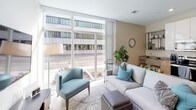 Located at 133 W Lovell St in downtown Kalamazoo, Michigan, this single-floor unit showcases a thoughtfully designed open-concept layout with a clean, contemporary aesthetic throughout. Light-toned flooring flows seamlessly across the living and sleeping areas, lending a cohesive and airy feel to the space.

The living area is anchored by expansive floor-to-ceiling windows that allow generous natural light to fill the room while offering direct views of the surrounding urban streetscape. The open design integrates the sleeping area naturally into the main living space, creating a flexible and functional environment.

The kitchen is well-appointed with white upper cabinetry, warm wood-toned lower cabinets, and granite countertops. A full suite of stainless steel appliances — including a refrigerator, range, microwave, and dishwasher — provides everything needed for everyday cooking. Light-colored tile flooring completes the clean, modern look.

The bathroom is finished to a high standard, featuring large-format gray tile walls and flooring, a spacious glass-enclosed walk-in shower with built-in niching, and a wood-tone vanity topped with granite. The bedroom area provides a quiet, comfortable retreat with warm neutral tones and thoughtfully placed wall sconce lighting. Overall, the space combines modern finishes with a functional layout suited for urban living.