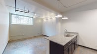 Located at 612 S Main St in downtown Burlington, NC, this single-floor unit blends industrial character with modern updates throughout. The open main area features polished concrete floors, a white-painted wood-plank ceiling with exposed beams, a ceiling fan, and track lighting that fills the space with a bright, airy atmosphere. A window brings in natural light, enhancing the loft-like feel of the room.

The kitchen is well-appointed with dark espresso cabinetry, granite countertops, and stainless steel appliances including an electric range, microwave, and dishwasher. A peninsula with a granite surface and undermount sink provides additional prep space and serves as a natural divider between the kitchen and the open living area.

The bathroom is clean and functional, featuring granite countertops atop dark cabinetry, a full tub-shower combination with a curved curtain rod, and tile flooring. A dedicated laundry area accommodates a stacked GE washer and dryer unit, adding everyday convenience.

With its open floor plan, industrial aesthetic, and modern fixtures, this space is well-suited for a variety of uses. The combination of polished concrete floors, updated finishes, and flexible layout makes it an ideal option for those seeking a versatile urban environment in Burlington's South Main corridor.