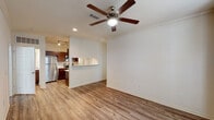 This single-story residence in Baton Rouge, Louisiana, offers a thoughtfully designed layout with consistent wood-look flooring flowing throughout the main living areas, bedroom, kitchen, and bathroom. The open living area is bright and spacious, featuring crown molding, recessed lighting, and a ceiling fan that adds both function and visual interest. A pass-through window connects the living space to the kitchen, enhancing the open feel between the two areas.

The kitchen is well-equipped with rich dark cabinetry, granite-style countertops, and a full suite of stainless steel appliances, including a refrigerator, electric range, built-in microwave, and dishwasher. Track lighting illuminates the workspace, and a doorway leads to an adjoining utility or storage area.

The bedroom is generously sized, filled with natural light from a window fitted with blinds, and features its own ceiling fan. The full bathroom mirrors the kitchen's design aesthetic with matching dark cabinetry, granite-style countertops, overhead storage, and a full-size soaking tub with shower combination. Clean white walls and neutral tones throughout create a cohesive, move-in-ready atmosphere.