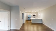 This single-floor residence on Moore Street in Fishers, Indiana, presents a thoughtfully designed layout with contemporary finishes throughout. The entryway, framed by a classic Craftsman-style door with brushed nickel hardware, sets a clean, modern tone upon arrival.

The kitchen serves as a central highlight, featuring grey shaker-style cabinetry, a white subway tile backsplash, and a full suite of stainless steel appliances including a French door refrigerator, range, and microwave. A generously sized island topped with white quartz countertops provides additional workspace and casual seating, illuminated by pendant lighting overhead. Rich hardwood-style flooring extends through the main living areas, adding warmth throughout.

The living area is bright and open, receiving natural light through large windows with views of the surrounding community. Ceiling fans are present throughout, including in the carpeted bedrooms, which offer a comfortable and quiet retreat. A second bedroom also benefits from natural light and a ceiling fan.

The bathroom is well-appointed, featuring a quartz-topped double vanity, dark hardwood-style flooring, and a marble-tiled walk-in shower enclosed in glass, conveying a refined, spa-like aesthetic.