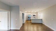 This single-floor residence on Moore Street in Fishers, Indiana, presents a thoughtfully designed layout with contemporary finishes throughout. The entryway, framed by a classic Craftsman-style door with brushed nickel hardware, sets a clean, modern tone upon arrival.

The kitchen serves as a central highlight, featuring grey shaker-style cabinetry, a white subway tile backsplash, and a full suite of stainless steel appliances including a French door refrigerator, range, and microwave. A generously sized island topped with white quartz countertops provides additional workspace and casual seating, illuminated by pendant lighting overhead. Rich hardwood-style flooring extends through the main living areas, adding warmth throughout.

The living area is bright and open, receiving natural light through large windows with views of the surrounding community. Ceiling fans are present throughout, including in the carpeted bedrooms, which offer a comfortable and quiet retreat. A second bedroom also benefits from natural light and a ceiling fan.

The bathroom is well-appointed, featuring a quartz-topped double vanity, dark hardwood-style flooring, and a marble-tiled walk-in shower enclosed in glass, conveying a refined, spa-like aesthetic.