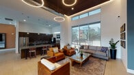 Located at 5151 N 95th Ave in Glendale, Arizona, this single-story community clubhouse at Copper Falls offers a well-appointed gathering space designed with a contemporary aesthetic throughout. The welcoming lounge area greets visitors with soaring ceilings, dramatic circular pendant lighting, and floor-to-ceiling windows that flood the space with natural light and provide views of the surrounding community. Rich leather seating in warm amber tones contrasts beautifully with neutral area rugs and modern accent furniture, creating an inviting atmosphere for socializing.

The fully equipped kitchen features dark wood cabinetry, mosaic tile backsplash, stainless steel appliances, a large central island with bar seating, and pendant lighting — ideal for community gatherings and events. Adjacent to the kitchen, a game and entertainment area includes a pool table, high-top bar seating, a wall-mounted television, and a two-sided fireplace column that anchors the space.

A dedicated business center provides a long communal desk with multiple computer workstations, hardwood flooring, and desert-themed artwork. A private conference room with large windows, roller shades, and a wood table offers a quiet space for meetings. Throughout the clubhouse, clean lines, neutral tones, and carefully curated furnishings contribute to a cohesive, modern ambiance.