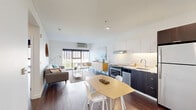 Located at 700 NE Multnomah St in Portland, Oregon, this thoughtfully designed single-floor residence offers a clean, contemporary aesthetic throughout. The open-concept living area seamlessly integrates the kitchen, dining, and living spaces, creating an efficient yet comfortable layout. Rich dark hardwood flooring flows throughout, providing a warm contrast to the bright white walls and ceilings.

The kitchen is well-appointed with two-tone cabinetry — crisp white uppers paired with dark lower cabinets — and a full suite of stainless steel appliances including a range, dishwasher, refrigerator, and built-in microwave. A dedicated dining area sits adjacent, offering space for everyday meals. The living room benefits from a large window that draws in generous natural light and frames urban views of the Portland skyline.

The bedroom is a calm retreat, featuring a floor-to-ceiling window with city views, a dedicated closet, and direct access to an in-unit stacked washer and dryer. The bathroom offers a clean, all-white design with a full tub-shower combination. Two closets provide practical storage, and the entrance area transitions smoothly into the main living space. Overall, the unit presents a modern, functional design well-suited for urban living in the heart of Portland.