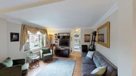 This well-appointed single-floor residence offers a cohesive and comfortable layout that balances classic design with everyday functionality. The living room serves as the heart of the home, showcasing warm hardwood flooring, elegant crown molding, and a large window dressed with decorative swag curtains that frame views of the surrounding neighborhood. The space accommodates both a relaxed seating area and a small desk nook, offering versatility for living and working. Natural light filters in generously, enhancing the inviting ambiance throughout.

The bedroom is a serene retreat, featuring plush carpeting, vibrant teal accent curtains, and a ceiling fan for year-round comfort. Windows with garden views and a classic white dresser with mirror add to the room's bright, tranquil character.

The kitchen is efficiently designed with warm wood cabinetry, sleek dark granite tile countertops, a full complement of appliances, and a window above the sink that brings in additional natural light. The layout maximizes counter and storage space for practical daily use.

The bathroom is clean and classic, featuring a full tub-shower combination with white tile surround, a pedestal-style sink, mirrored medicine cabinet, and a small window for ventilation. The overall space presents a timeless, well-maintained interior with thoughtful details throughout.