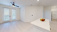 Unit 312 at 900 E Sligh Ave in Tampa, Florida presents a thoughtfully designed one-bedroom, two-bathroom residence that maximizes its efficient single-floor layout. The kitchen serves as a standout feature, showcasing white shaker cabinetry with black hardware, quartz countertops, a subway tile backsplash, and a full suite of stainless steel appliances. A generous island provides additional prep and dining space, while light wood-look flooring runs throughout the main living areas, complementing the bright, neutral color palette. The open living area benefits from natural light through large windows with outdoor views of surrounding greenery, and is outfitted with a ceiling fan. The spacious primary bedroom features plush carpeting, a ceiling fan, and a well-sized walk-in closet with multi-tiered wire shelving for organized storage. Both bathrooms reflect a clean, modern aesthetic with white vanities, quartz surfaces, black-framed mirrors, and matte black fixtures. The second bathroom includes a frameless glass walk-in shower with marble-style tile surround and a sleek black door handle. Overall, the unit delivers a cohesive, contemporary feel throughout.