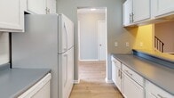 Located at 300 Audubon Pkwy in Syracuse, NY, this two-floor residence offers a well-organized layout with updated finishes throughout. The main living area features light wood-tone flooring and neutral gray walls, creating a bright and open atmosphere. A mirrored accent wall reflects natural light and adds a sense of depth to the space. The kitchen is outfitted with white cabinetry, brushed nickel hardware, gray countertops, and white appliances, connecting seamlessly to adjacent living areas via an open passageway. Two bathrooms are present in the home — one featuring marble-style tile flooring, a white vanity with a dark faucet fixture and medicine cabinet mirror, and a clean, modern aesthetic. The second bathroom includes a white vanity and a window for natural ventilation. The bedrooms are carpeted in soft gray tones, with warm beige walls and ample natural light provided by multiple windows with white blinds. One bedroom features a full mirrored sliding closet door, enhancing the sense of space. Additional bedrooms offer dedicated HVAC vents and generous square footage. Textured ceilings are present in select rooms. Overall, the residence presents a functional and refreshed interior well-suited for comfortable everyday living.