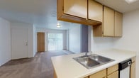 This single-floor residence offers a functional and straightforward layout designed for comfortable everyday living. The kitchen is equipped with light wood cabinetry providing ample storage, a double-basin sink set into a light-colored countertop, a white electric range, and a refrigerator. Tile flooring anchors the kitchen area, which opens directly to the living space, creating a connected, open feel. The living area features soft carpeting and is brightened by a large sliding glass door fitted with vertical blinds, offering access to the outdoors and allowing generous natural light to fill the space. A separate entry door with tile flooring marks a defined entryway.

The bedrooms are carpeted and finished with neutral white walls, each featuring windows with blinds that bring in outdoor views and natural light, contributing to a bright and airy atmosphere. The bathrooms are cleanly appointed with tub and shower combinations, tile flooring, and wood-toned vanity cabinetry. A dedicated laundry room includes tile flooring, a wire storage shelf, and connections for a washer and dryer, adding practical convenience to the unit's overall functionality.
