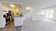 This single-floor residence features three bedrooms and two full bathrooms within a thoughtfully arranged layout. The open living area is finished with plush wall-to-wall carpeting and connects seamlessly to the kitchen via an arched pass-through, creating a cohesive shared space. The galley-style kitchen is equipped with stainless steel appliances, including a refrigerator, gas range, and dishwasher, complemented by white cabinetry, dark countertops, and wood-look plank flooring that adds warmth and durability. Each of the three bedrooms is carpeted and finished with neutral tones, offering a clean and versatile backdrop. Select bedrooms feature windows that invite natural light and outdoor views, while at least one includes a built-in closet with shelving. Both bathrooms are finished with tile-surround tub-shower combinations, wood-look flooring, and classic white fixtures, maintaining a consistent, clean aesthetic throughout. The overall design emphasizes practicality and comfort, with a neutral color palette and straightforward layout making the space adaptable to a variety of furnishing styles.