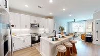 Located at 640 Lakeside Dr in Canton, Georgia, this thoughtfully designed two-bedroom, two-bathroom residence offers a comfortable and modern single-floor layout. The open-concept kitchen and living area serves as the heart of the home, featuring a white shaker-style kitchen with quartz countertops, a center island with bar seating, stainless steel appliances, a subway tile backsplash, and matte black hardware. The kitchen flows seamlessly into the bright living room, where large windows frame outdoor views and a ceiling fan adds a practical touch. Light wood-tone flooring runs throughout, contributing to a warm and cohesive aesthetic. Both bedrooms are generously sized, each equipped with ceiling fans, large windows that invite natural light, and access to well-organized closets with wire shelving systems. The primary bedroom features a spacious walk-in closet. Both bathrooms include white shaker vanities, bold black-framed mirrors, and matte black fixtures, offering a clean, contemporary look. A dedicated laundry room houses a full-size front-loading washer and dryer with overhead shelving for additional storage. The overall ambiance is bright, modern, and functional, making this a well-rounded residence in Canton, Georgia.