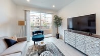 This well-appointed single-floor residence offers a clean, modern aesthetic throughout, characterized by light wood-style flooring, crisp white walls, and recessed lighting that creates a bright and welcoming atmosphere. The open living area is anchored by a sliding glass door that leads to a private balcony, filling the space with natural light and offering views of the surrounding neighborhood. The kitchen is thoughtfully designed with white shaker cabinetry, dark countertops, and a full suite of stainless steel appliances including a gas range, microwave, and refrigerator. A dedicated dining area adjacent to the entry provides a practical and comfortable space for meals. The primary bedroom is generously sized and features a walk-in closet and direct access to a full en-suite bathroom with a dual-sink vanity, tub-shower combination, and light wood-style flooring. Two additional bedrooms are well-proportioned, each with windows that bring in natural light. A second full bathroom mirrors the clean design of the primary bath, complete with a vanity and tub-shower. A stacked in-unit washer and dryer adds everyday convenience. The overall design is cohesive and contemporary, with a neutral palette that carries consistently through every room.