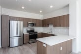 Located at 703 N Main St in Meridian, Idaho, this single-floor 2-bedroom, 2-bathroom unit showcases a clean, contemporary design with a cohesive neutral palette throughout. Light-toned luxury vinyl plank flooring runs continuously across all rooms, contributing to a bright, airy atmosphere.

The open-concept kitchen is a standout feature, equipped with warm wood-grain cabinetry, light quartz countertops, and a subway tile backsplash. A peninsula island provides additional prep space and separates the kitchen from the living area. Stainless steel appliances, including a refrigerator, gas range, microwave, and dishwasher, complete the functional layout. A wall-mounted mini-split system provides climate control.

Both bathrooms feature matching wood-toned vanities with quartz countertops and large mirrors framed by overhead lighting. One bathroom includes a walk-in shower, while the other offers a full soaking tub. Each is finished with the same light flooring found throughout the unit.

The bedrooms are well-lit with multiple windows offering exterior views, and each includes ample closet space. One bedroom features a spacious walk-in closet with multiple hanging rods and shelving. The overall design emphasizes clean lines, functional storage, and consistent modern finishes throughout the space.