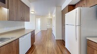Located at 3500 S Sherman St in Englewood, Colorado, this two-bedroom, one-bathroom residence offers a practical and well-organized single-floor layout. The kitchen is a standout feature, equipped with rich walnut-toned cabinetry that extends to the ceiling for generous storage, a full suite of white appliances including a refrigerator, electric range, microwave, and dishwasher, and durable wood-style flooring. The kitchen opens directly to the living room, which transitions to plush carpeting and connects to a private balcony that brings in natural light and outdoor views. Both bedrooms are carpeted and feature sliding-door closets, offering comfortable and functional personal spaces. The second bedroom benefits from a large window framing open outdoor views. The full bathroom includes wood-style flooring, a bathtub with grab bars, and direct access to an adjacent closet with built-in wire shelving. Additional highlights include a dedicated laundry area, a welcoming entrance, and three closets throughout the unit for ample storage. The neutral color palette and clean finishes throughout give the space a bright, move-in-ready feel.