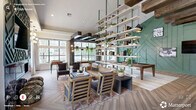 Located at 3333 Melrose Club Boulevard in Raleigh, NC, this thoughtfully designed single-floor clubhouse offers a generously proportioned communal space that blends sophisticated style with functional amenities. The expansive living room serves as the heart of the space, anchored by a striking sage-green geometric accent wall housing a linear fireplace and mounted television. Vaulted ceilings amplify the sense of openness, while large floor-to-ceiling windows flood the interior with abundant natural light and offer views of the surrounding greenery. A dramatic multi-tiered open bookshelf, suspended with green metal poles and adorned with books and trailing plants, serves as an architectural centerpiece and natural room divider. Rich herringbone-patterned hardwood flooring flows throughout, complemented by exposed dark wood beam accents that add warmth and contrast. A dedicated game area features a full-size billiards table beneath stylish pendant lighting, alongside a foosball table near the windowed wall. Dark wood structural columns frame expansive windows, creating an industrial-chic aesthetic. A quieter retreat room offers a calming sage and blush palette with natural wood paneling, a lounge chaise, and a window seat — ideal for relaxation or focused work. The hallway connects these distinct zones seamlessly, creating a cohesive and inviting environment throughout.