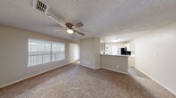 This single-story 2-bedroom, 2-bathroom home features a practical and efficient floor plan designed for comfortable everyday living. The open living area is finished with plush carpet and a ceiling fan overhead, while large windows with white blinds allow ample natural light to fill the space. A textured ceiling adds a classic touch throughout the main living areas and bedrooms.

The kitchen is designed for functionality, featuring white cabinetry extending to the ceiling for generous storage, light countertops, black appliances including an electric range and dishwasher, and a peninsula that opens toward the living area — ideal for casual dining or entertaining.

Both bedrooms are carpeted and well-sized, with windows providing natural light. The primary bedroom includes a ceiling fan and access to a spacious walk-in closet outfitted with wire shelving and hanging rods for organized storage. A second closet offers additional storage space.

The two bathrooms feature wood-look flooring, white fixtures, and tub-shower combinations. The primary bathroom includes a long vanity with ample counter space and a large mirror, while the second bathroom offers a similar clean, functional layout.

A dedicated laundry room includes washer/dryer hookups, wire shelving, and a window for natural light, completing this well-appointed home.