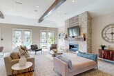 Located at 51401 Times Square Dr in Shelby Township, MI, this single-floor community clubhouse offers a thoughtfully designed layout spanning a generous footprint. The centerpiece of the space is a bright, open lounge area distinguished by soaring vaulted ceilings with decorative exposed wood beams and recessed lighting. A striking floor-to-ceiling stacked-stone fireplace anchors one wall, while a bank of French doors lines the opposite side, flooding the room with natural light and providing views of the surrounding community. Hardwood flooring transitions to plush area rugs, creating distinct seating and dining zones within the lounge.

The kitchen is outfitted with rich dark-wood cabinetry, granite countertops, a center island with bar seating, a tile backsplash, and stainless steel appliances, including a gas range topped by a professional hood. A modern chandelier adds an elegant finishing touch overhead.

The fitness center is divided into two well-equipped areas: a cardio room with treadmills, an elliptical, and a stationary bike beneath an arched window, and a separate strength training room housing dumbbells, medicine balls, and a leg press machine on durable rubber flooring. The space also includes three private offices, two hallways, a welcoming entrance, and a closet, making it fully functional for community activities and administration.