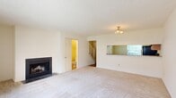 This two-story home in Richmond, Virginia offers a practical and comfortable layout across two floors, featuring three bedrooms and three full bathrooms. The main level hosts a spacious living room with light carpet, a wood-burning fireplace, and a pass-through window connecting to the kitchen, which adds an open, airy feel to the shared living space. A staircase conveniently located off the living room leads to the upper level. The kitchen is well-equipped with warm wood cabinetry, granite-look countertops, hardwood-style flooring, and black appliances including a range, refrigerator, and dishwasher. A full bathroom on the main floor features tile flooring, a vanity with wood cabinetry, and a bathtub. Upstairs, three carpeted bedrooms offer natural light through multiple windows with blinds. The generously sized primary bedroom provides ample space for comfortable living. Additional bedrooms are well-proportioned with neutral tones and textured ceilings throughout. A sliding glass door in one of the rooms opens to the outdoors, bringing in natural light and exterior views. The bathrooms are clean and functional, each with a vanity and mirror. Overall, the home presents a straightforward, move-in ready layout suited for everyday living.
