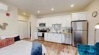 Located at 3120 W Fourth Ave in Kennewick, Washington, this thoughtfully designed studio unit offers a bright and functional single-floor layout that maximizes every square foot. The open-concept living area seamlessly integrates the sleeping, living, and kitchen spaces, creating an efficient and welcoming atmosphere throughout.

The fully equipped kitchen is a standout feature, showcasing crisp white shaker cabinetry extending to the ceiling for generous storage, granite-look countertops, and a full suite of stainless steel appliances including an electric range, over-the-range microwave, dishwasher, and a full-size refrigerator. Warm-toned wood-look flooring runs continuously throughout the unit, lending a cohesive and contemporary feel.

The main living space is bright and airy, benefiting from multiple windows fitted with white blinds that allow for natural light while maintaining privacy. A dedicated sleeping area flows naturally into the living space, complemented by a cozy sitting nook ideal for dining or relaxing.

A separate bathroom features a shower with a curtain enclosure and practical storage, accessible via a short hallway that also leads to a closet. Recessed lighting throughout enhances the clean, modern aesthetic. The unit's neutral color palette and efficient design make it a comfortable and versatile living space.