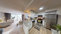 This well-appointed single-floor residence offers a thoughtfully designed open-concept layout that seamlessly connects the kitchen, dining, and living areas. The kitchen is outfitted with white shaker-style cabinetry, granite countertops, a subway tile backsplash, stainless steel appliances including a refrigerator, range, microwave, and dishwasher, and a peninsula that provides additional prep and seating space. Light wood-style flooring flows throughout the main living areas, enhancing the bright and airy atmosphere. The spacious living room features large sliding glass doors that open to a private patio, inviting abundant natural light and outdoor views. A separate dining area with direct sightlines to the kitchen adds to the functional flow of the space. The primary bedroom offers a calm, neutral palette with plush carpeting, dual windows, and generous natural light, complemented by its own full bathroom featuring a shower-tub combination. A second bedroom is carpeted and well-lit, with outdoor views through multiple windows. A versatile third room serves as a dedicated home office, complete with built-in shelving and a ceiling fan. The second full bathroom features a walk-in shower. Throughout, the residence maintains a cohesive, contemporary aesthetic with clean lines and a neutral color scheme.