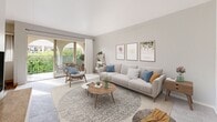 This 820 square foot apartment offers a well-designed layout with 2 bedrooms and 2 bathrooms. The open-plan living area combines the kitchen, dining, and living spaces, creating a sense of spaciousness. The kitchen features white cabinetry, light countertops, and modern appliances, with a galley-style layout for efficiency.

The primary bedroom, measuring 160 square feet, provides ample space and includes a large window for natural light. Both bedrooms are carpeted and decorated in neutral tones, with the primary bedroom showcasing a decorative wall hanging and round area rug.

The bathrooms are clean and functional, with one featuring a vanity and mirror. The living room is tastefully furnished with a light grey sofa, wooden coffee table, and rattan accent chair. Large windows and sliding glass doors in the living area lead to an outdoor space, likely a balcony or patio.

Throughout the apartment, a cohesive color scheme of whites, greys, and light woods is complemented by touches of blue in the furnishings. The flooring alternates between carpet in the bedrooms and wood-look laminate in the main living areas and kitchen. Overall, the space exudes a modern, minimalist aesthetic with attention to both style and functionality.