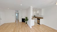 This single-floor space offers a clean, modern aesthetic defined by light hardwood flooring, crisp white walls, and crown molding throughout. The open-concept living area is generously proportioned, with recessed lighting and a fireplace serving as a focal point. Plantation shutters on select windows allow for adjustable natural light, contributing to the unit's airy, welcoming ambiance.

The kitchen is efficiently designed in a galley layout, featuring white shaker cabinetry extending to the ceiling, granite countertops, stainless steel appliances including a gas range, dishwasher, and microwave, and tile flooring. A decorative column separates the kitchen from the living space, adding architectural character without interrupting the open flow.

The bedrooms are well-sized, each equipped with ceiling fans, plantation shutters, and hardwood flooring. One bedroom includes a mirrored sliding-door closet, maximizing both storage and the sense of space. A hallway connects the sleeping areas, with access to additional rooms visible through doorways.

The bathrooms are finished with neutral stone-look tile, granite-topped vanities with white cabinetry, and frameless glass-enclosed showers, lending a polished, spa-like quality to the space.