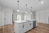 This well-appointed single-floor residence offers a thoughtfully designed layout with contemporary finishes throughout. The open-concept kitchen serves as the heart of the home, featuring crisp white shaker cabinetry with matte black hardware, a large island with an integrated sink and white quartz countertops, and stainless steel appliances including a refrigerator, range, and built-in microwave. Stylish globe pendant lights hang above the island, adding a modern touch. Light-toned hardwood flooring extends through the main living areas, creating a bright and cohesive feel. The spacious living area is bathed in natural light and opens directly to a private balcony through sliding glass doors, offering pleasant outdoor views. The bedrooms are comfortably sized, each finished with plush carpet flooring and windows that invite natural light. The bathrooms are clean and functional — one features a white vanity with quartz countertop, a framed mirror, and modern lighting, while another includes a walk-in shower. A louvered closet door and ample storage add practical convenience throughout. The overall aesthetic is fresh and modern, with neutral tones, recessed lighting, and clean lines defining every room.